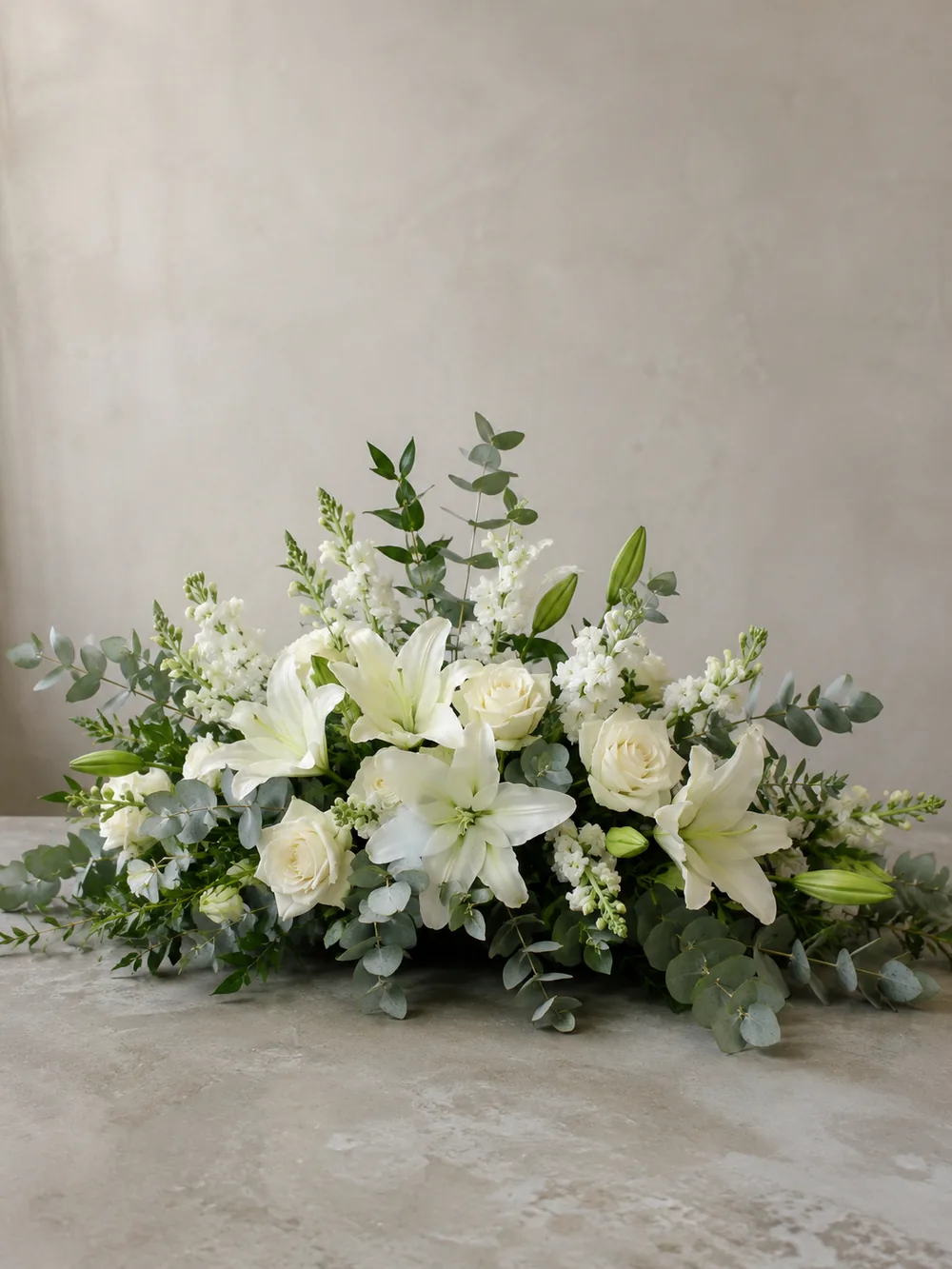 Funeral arrangement of white flowers on a base