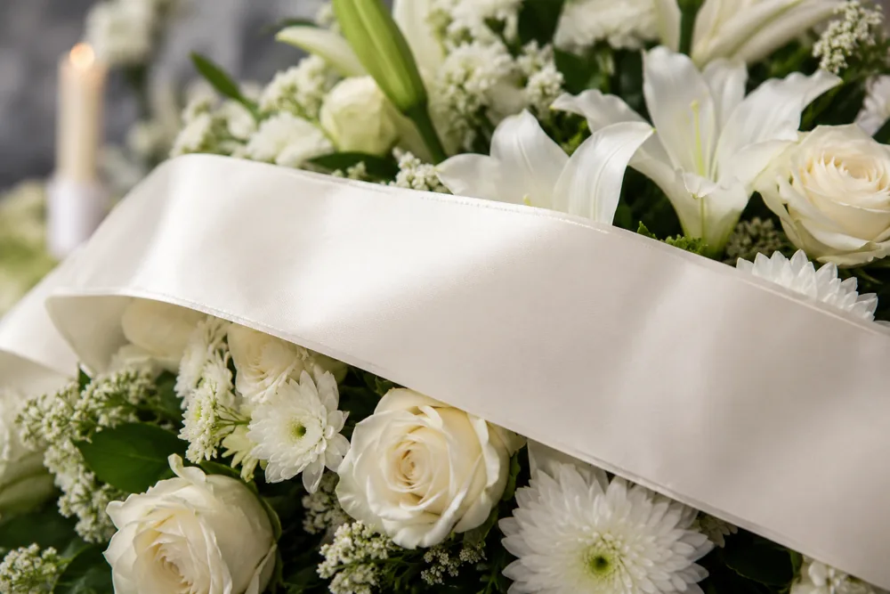 Cinta de condolencias en un arreglo de flores para tanatorio